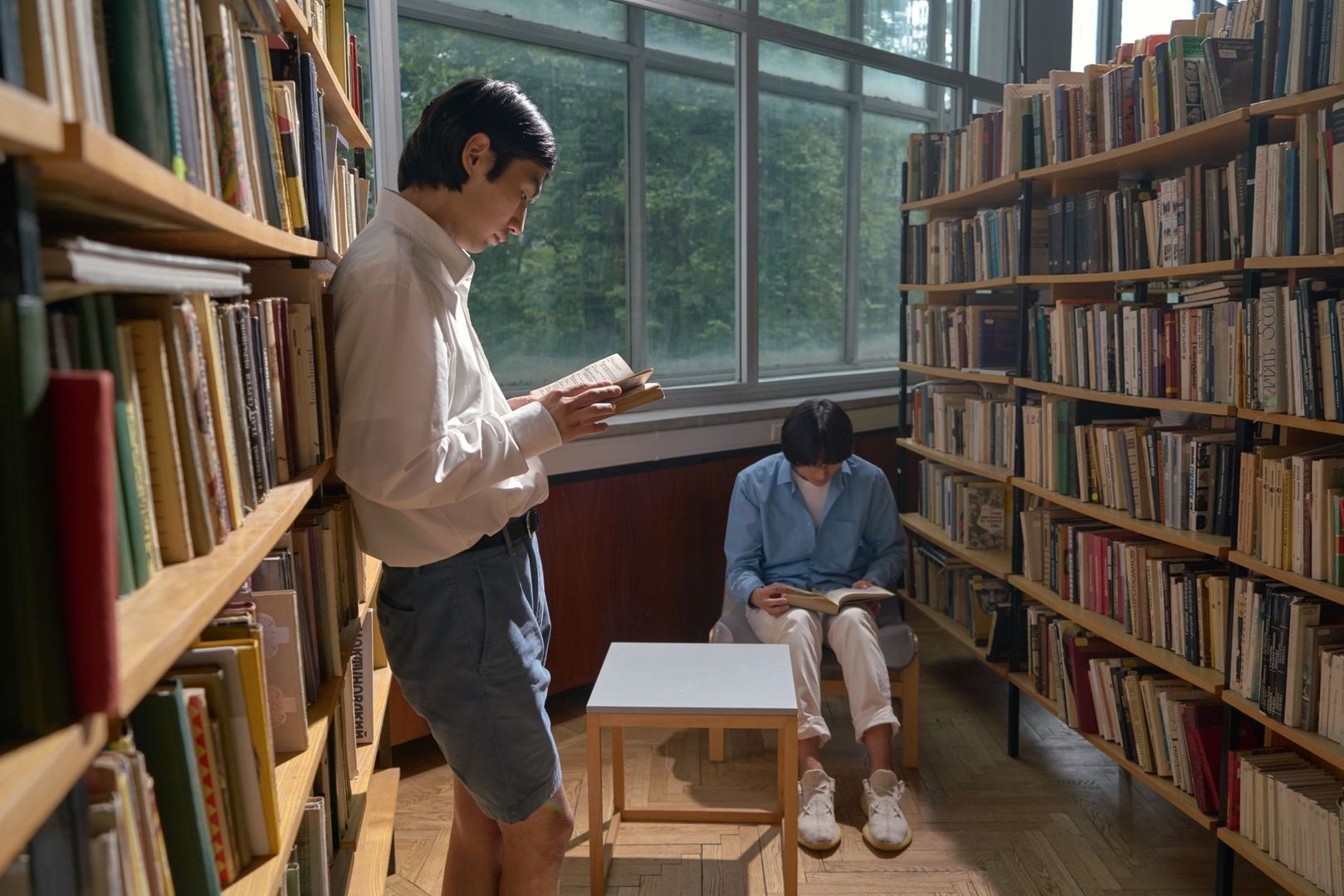 Zwei Menschen lesen zwischen Bücherregalen in einer Bibliothek
